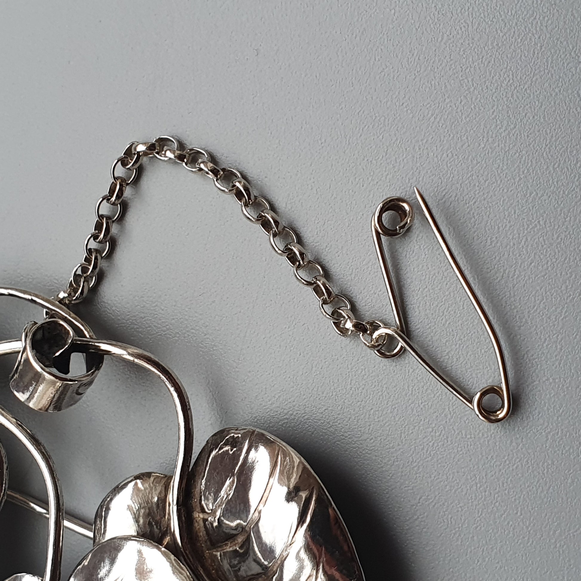 Safety pin alongside a silver chain and other metallic objects.