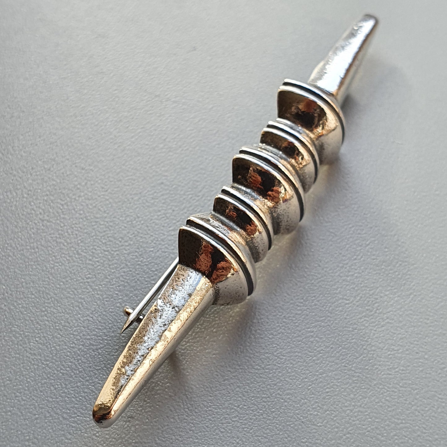 Metal spike or pin with multiple ridged bands around its shaft.