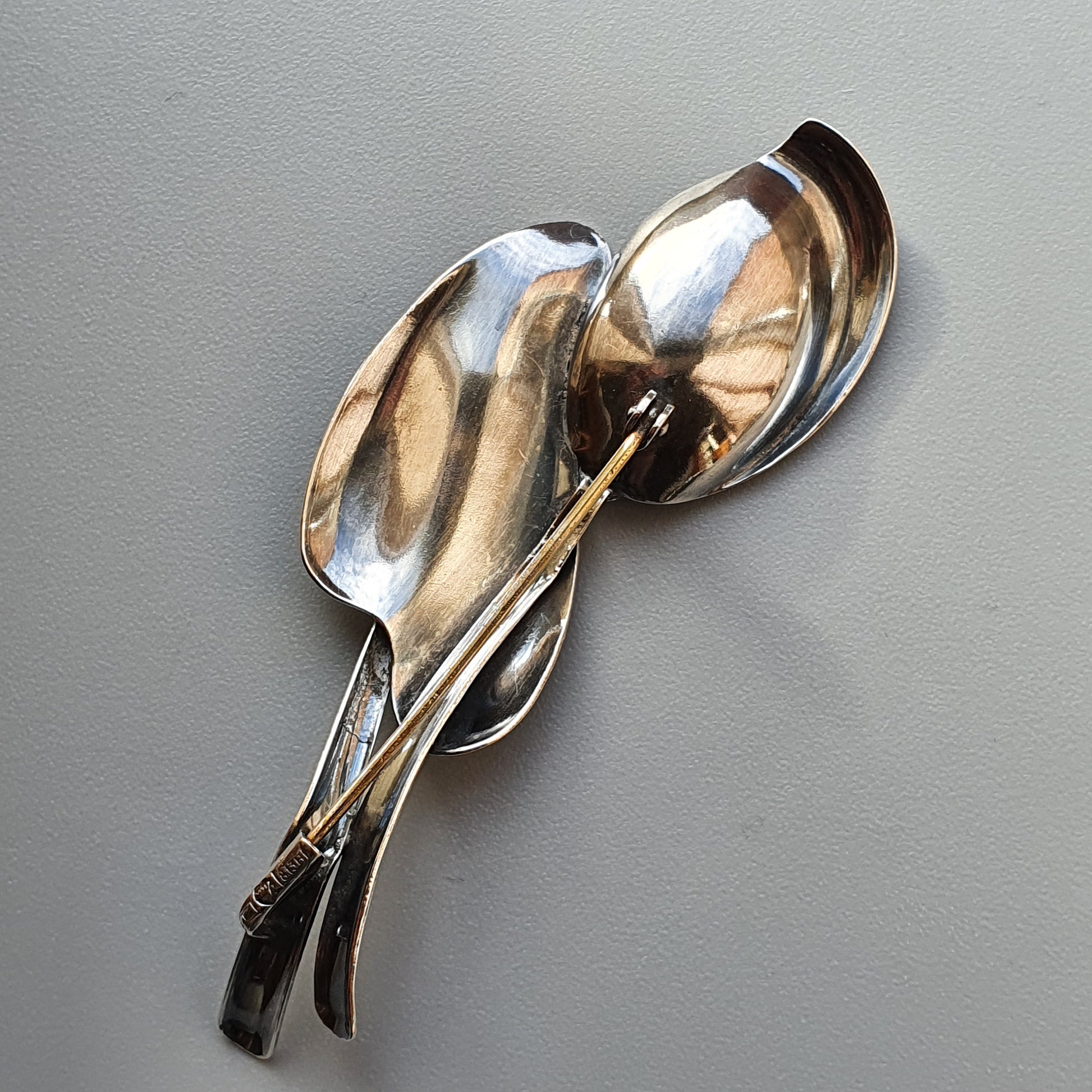 Cluster of shiny metal spoons arranged in an artistic, overlapping composition.