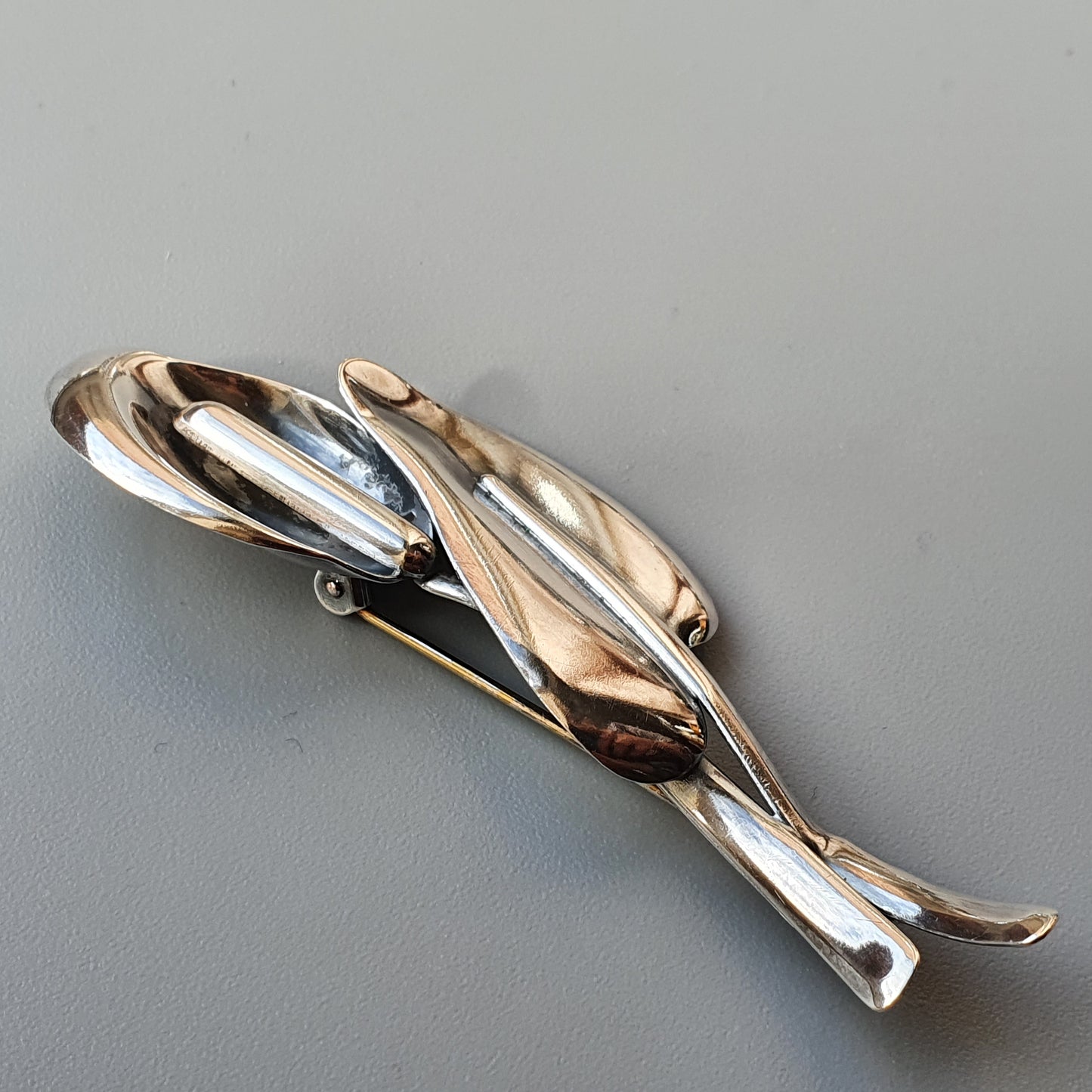 Silver-toned brooch or pin shaped like a stylized dolphin or fish.