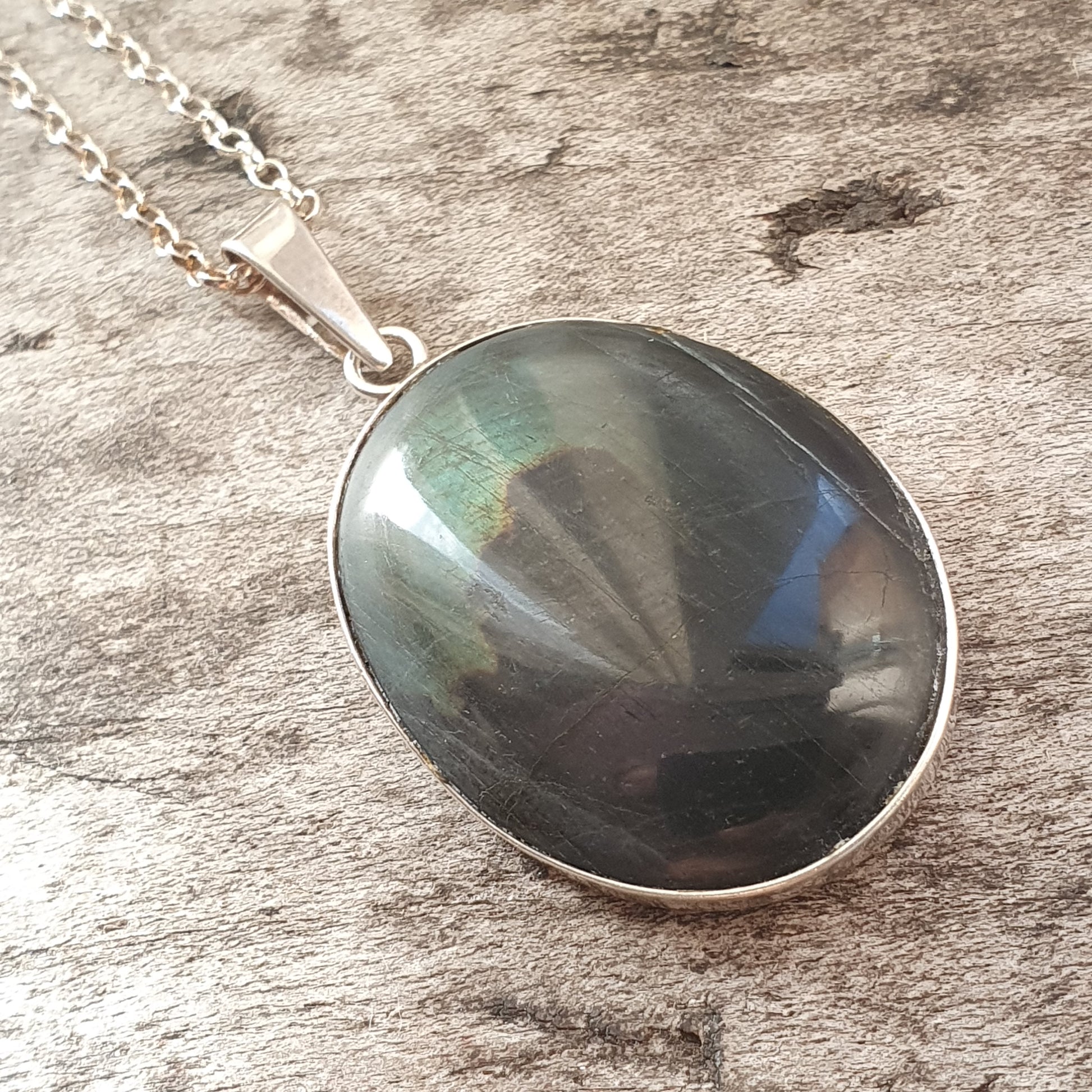 Oval pendant necklace featuring a dark, iridescent gemstone set in silver.