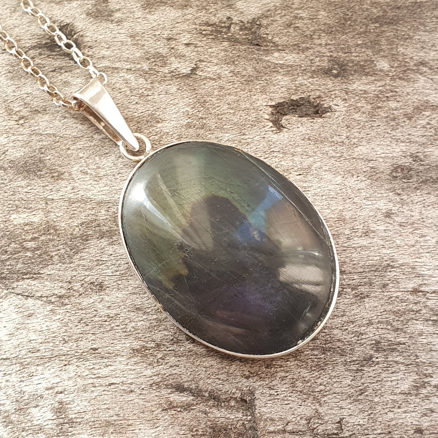 Oval pendant necklace with a dark, iridescent gemstone.