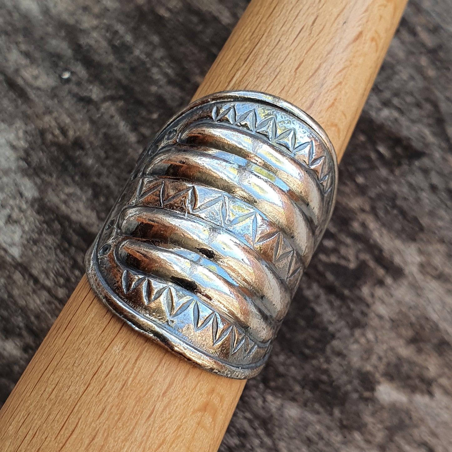 Wide silver ring with multiple bands and engraved geometric patterns.