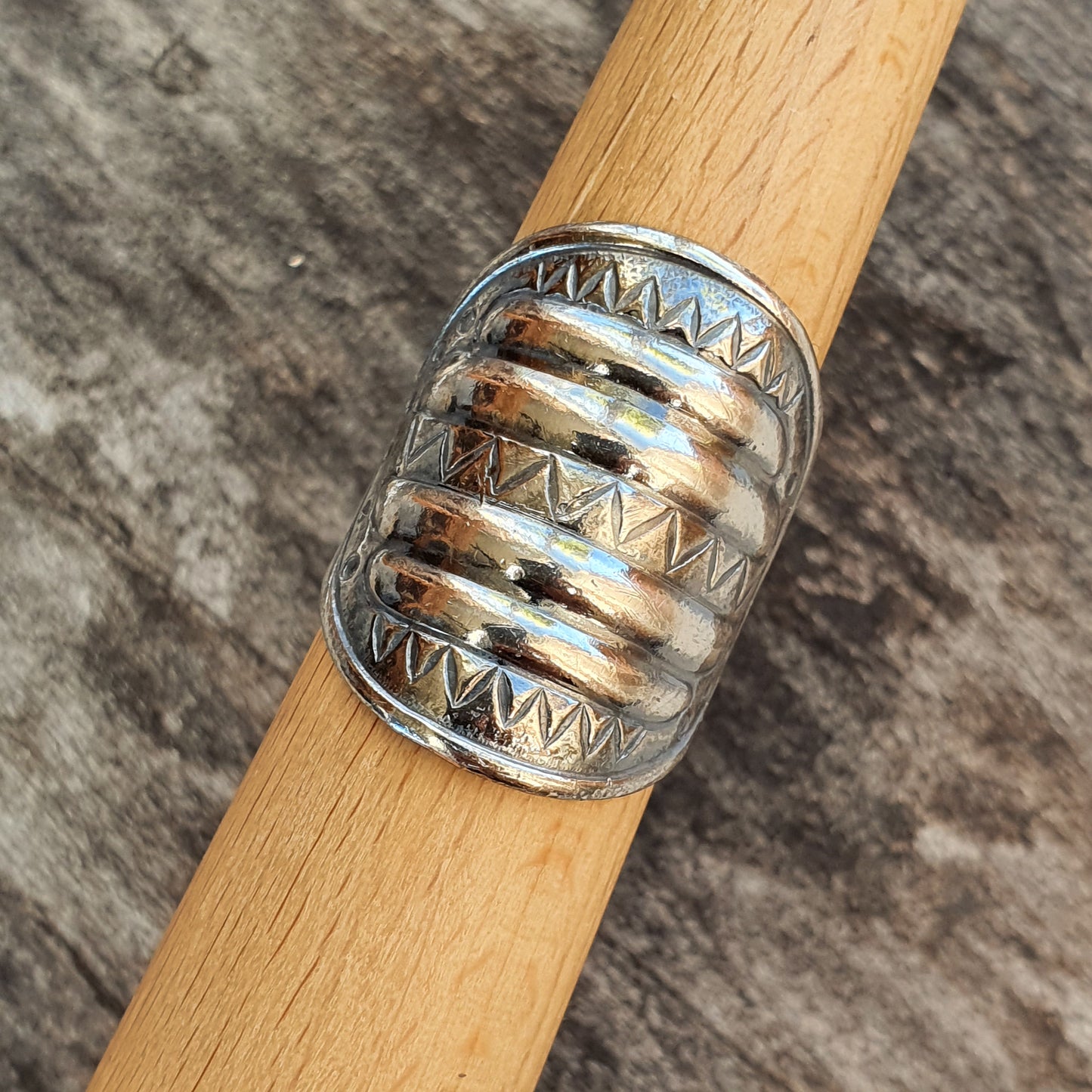 Silver ring with a wide band featuring engraved zigzag patterns.