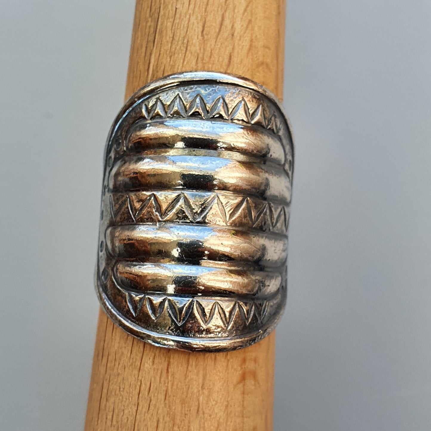 Wide silver ring with ribbed design and zigzag patterns.