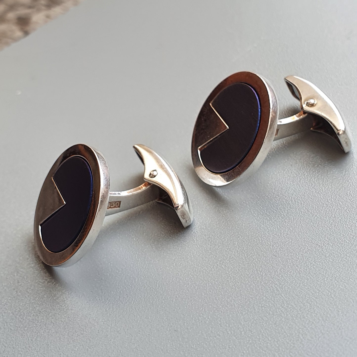 Pair of oval silver cufflinks with dark inlaid centers.