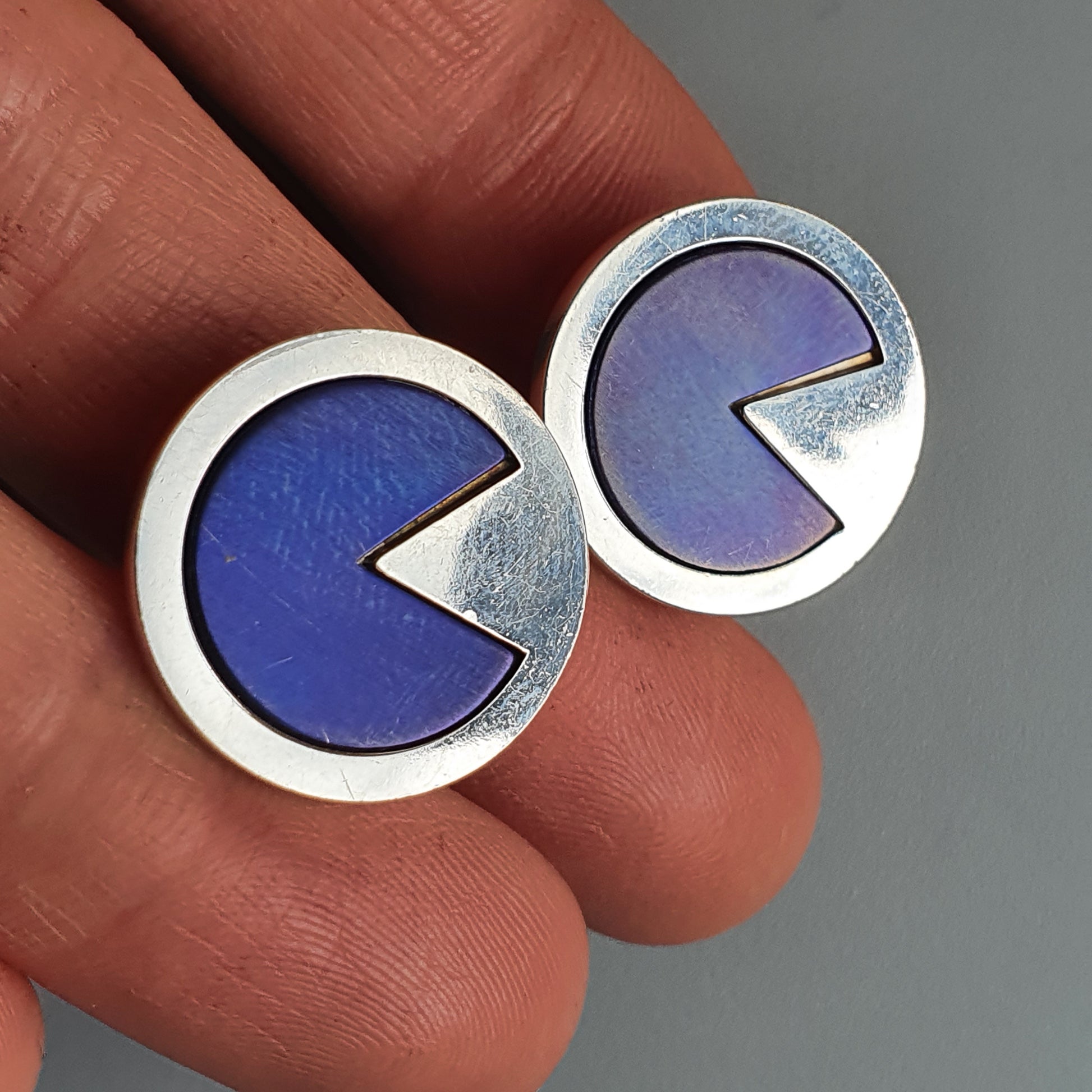 Pair of circular earrings or cufflinks with a Pac-Man-like design in blue and silver.