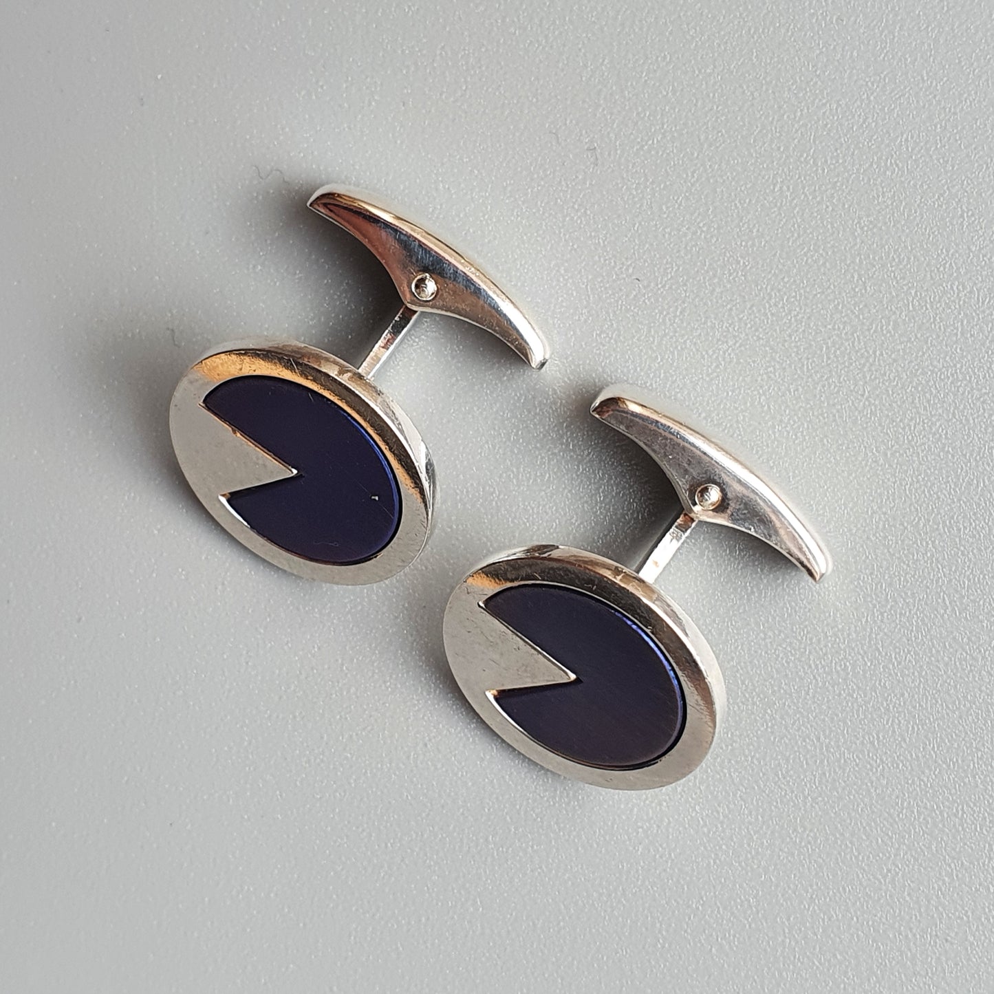 Pair of oval silver cufflinks with dark blue enamel inlays.