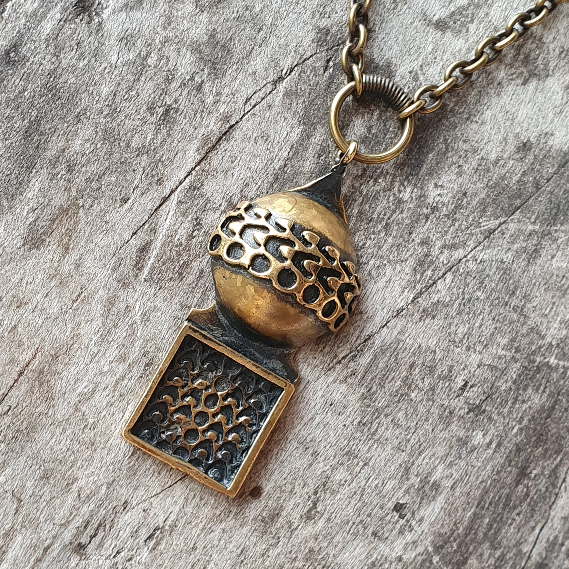 Antique-style brass pendant necklace with intricate honeycomb patterns.