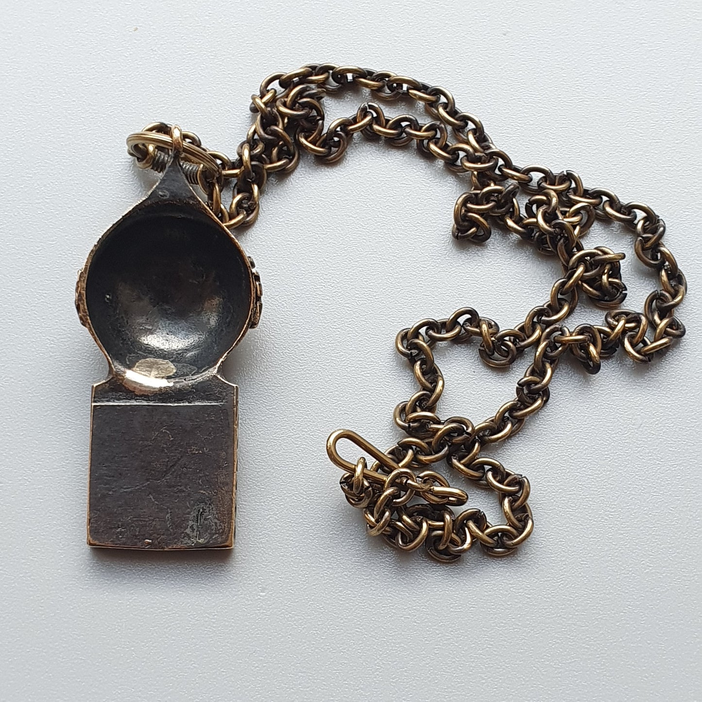 Antique-looking metal whistle pendant on a chain necklace.