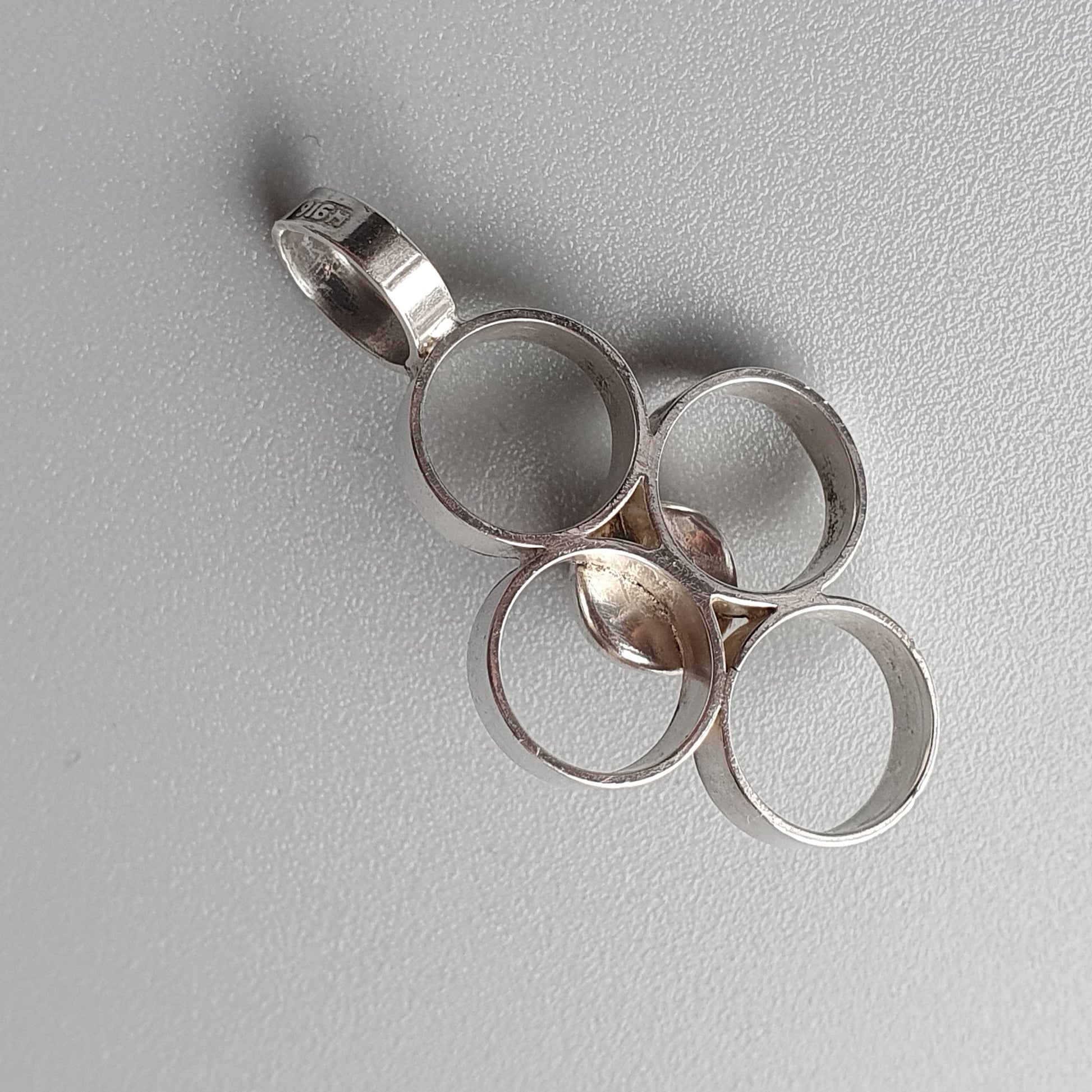 Silver pendant featuring interconnected circular rings in a clustered design.