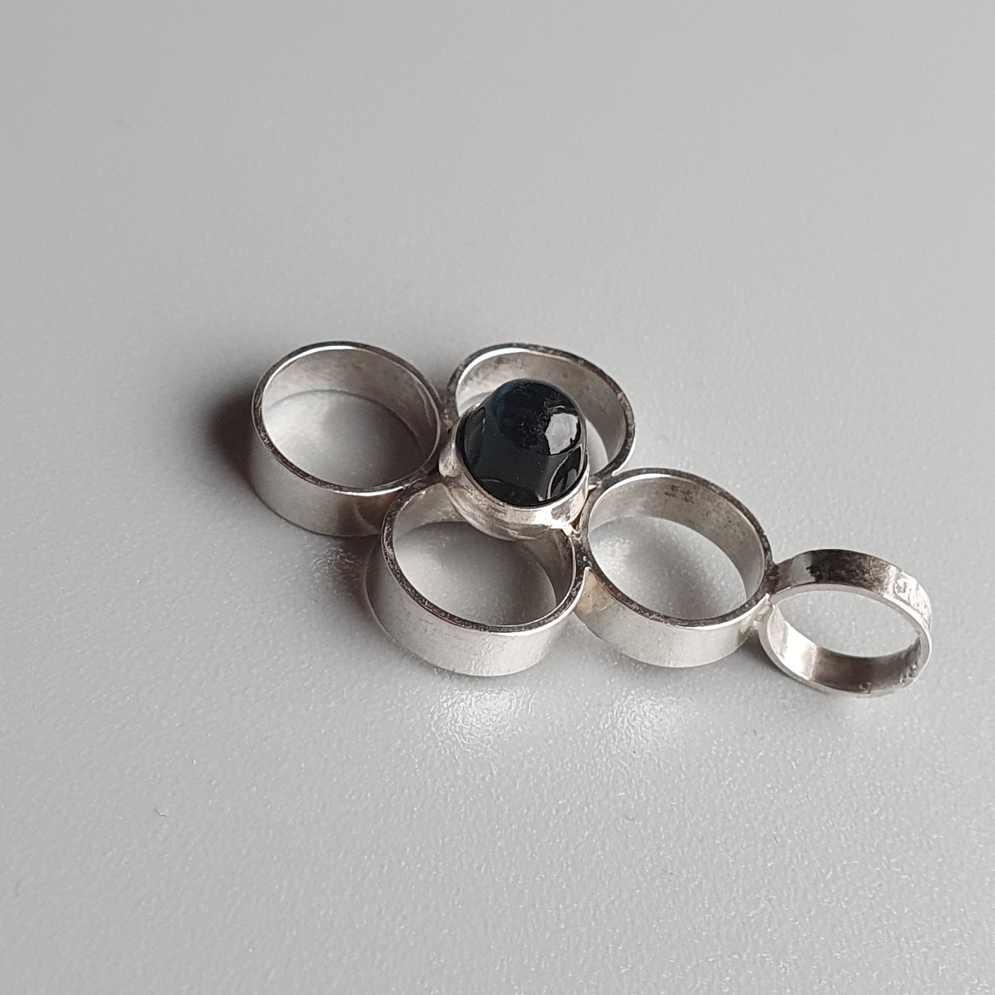 Set of five silver rings, one featuring a dark gemstone.