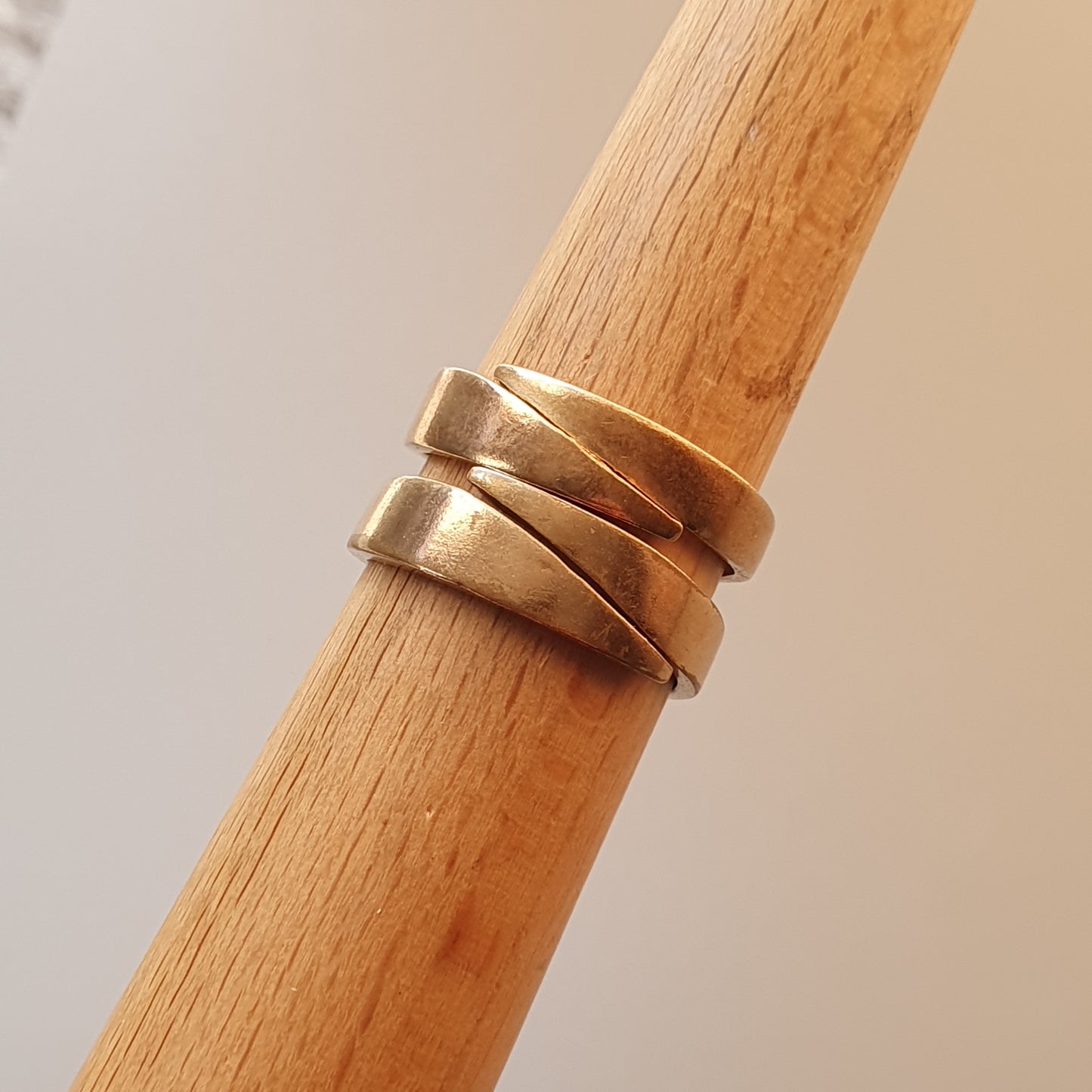 Gold-toned spiral ring wrapped around a wooden dowel.