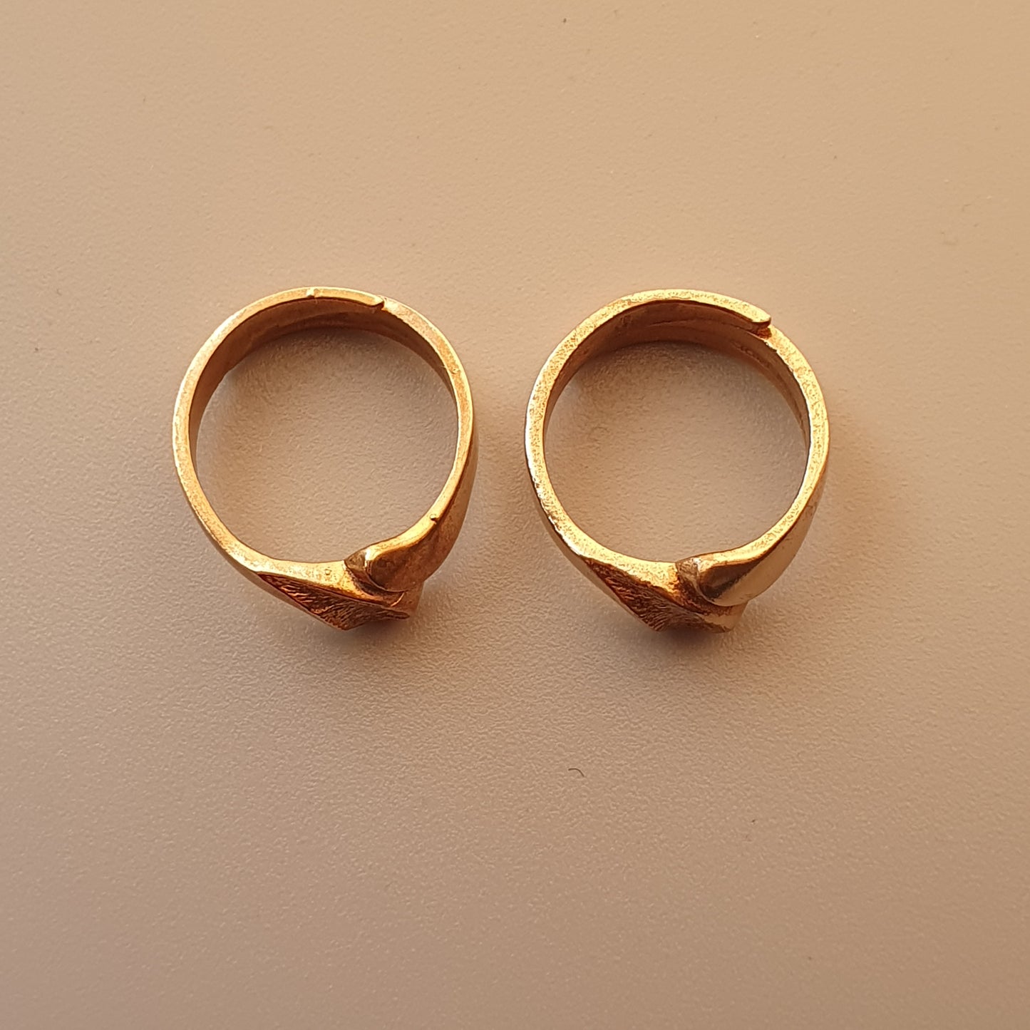 Pair of gold-colored rings with small decorative elements on their bands.