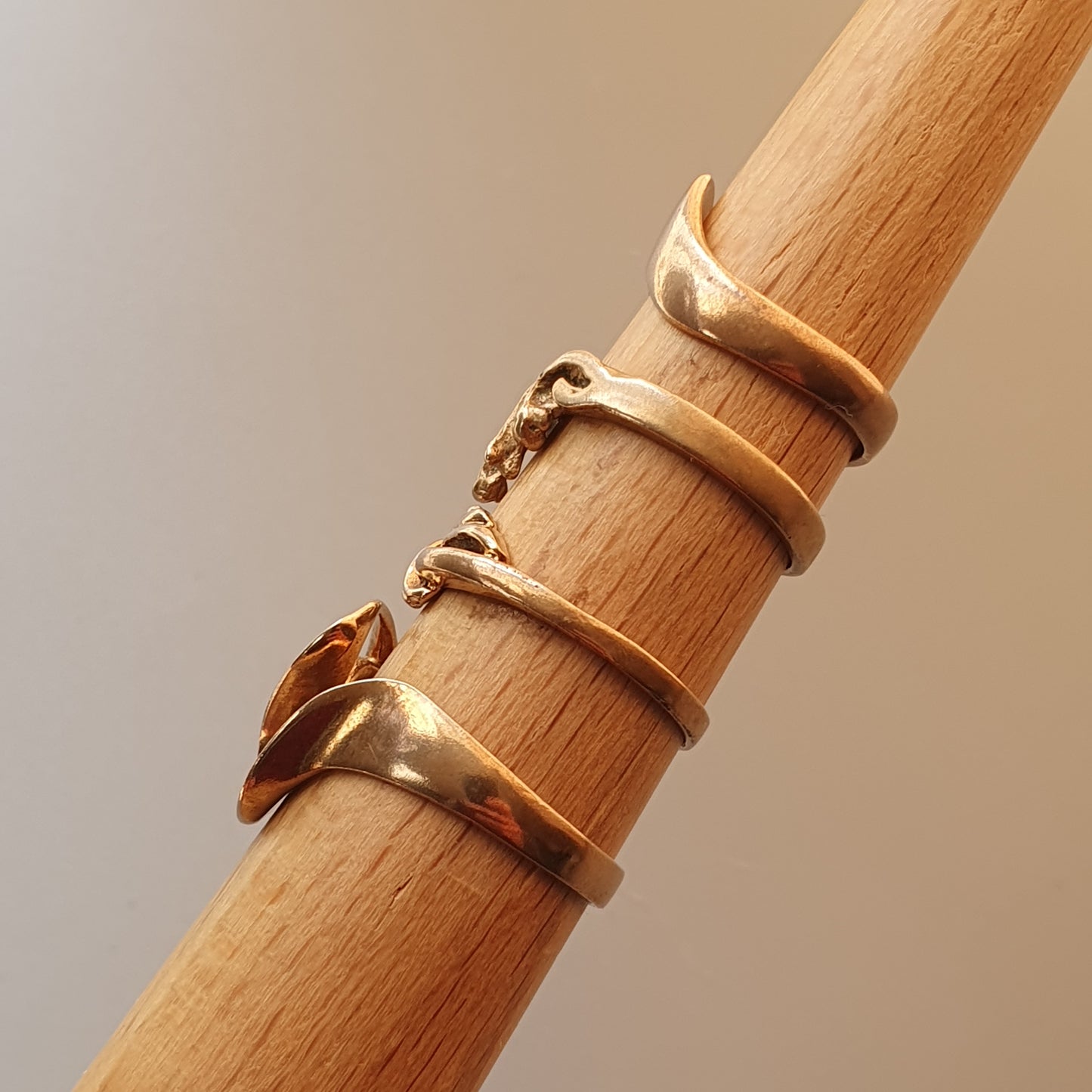 Three gold rings stacked on a wooden dowel or rod.