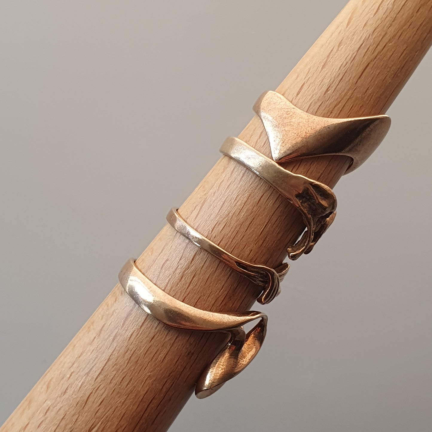 Wooden dowel or rod with several gold-toned rings wrapped around it.