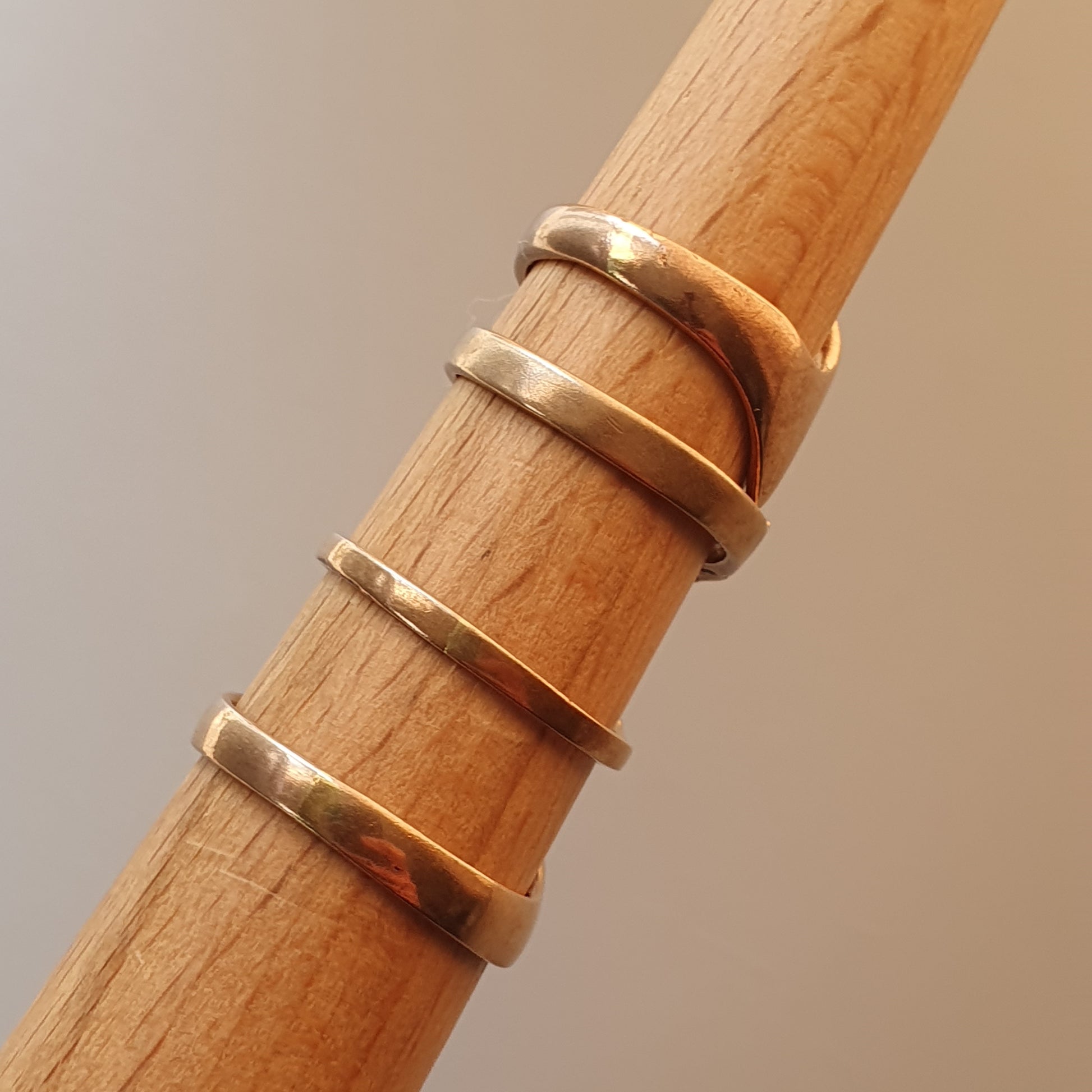 Wooden dowel or rod with four gold rings wrapped around it.