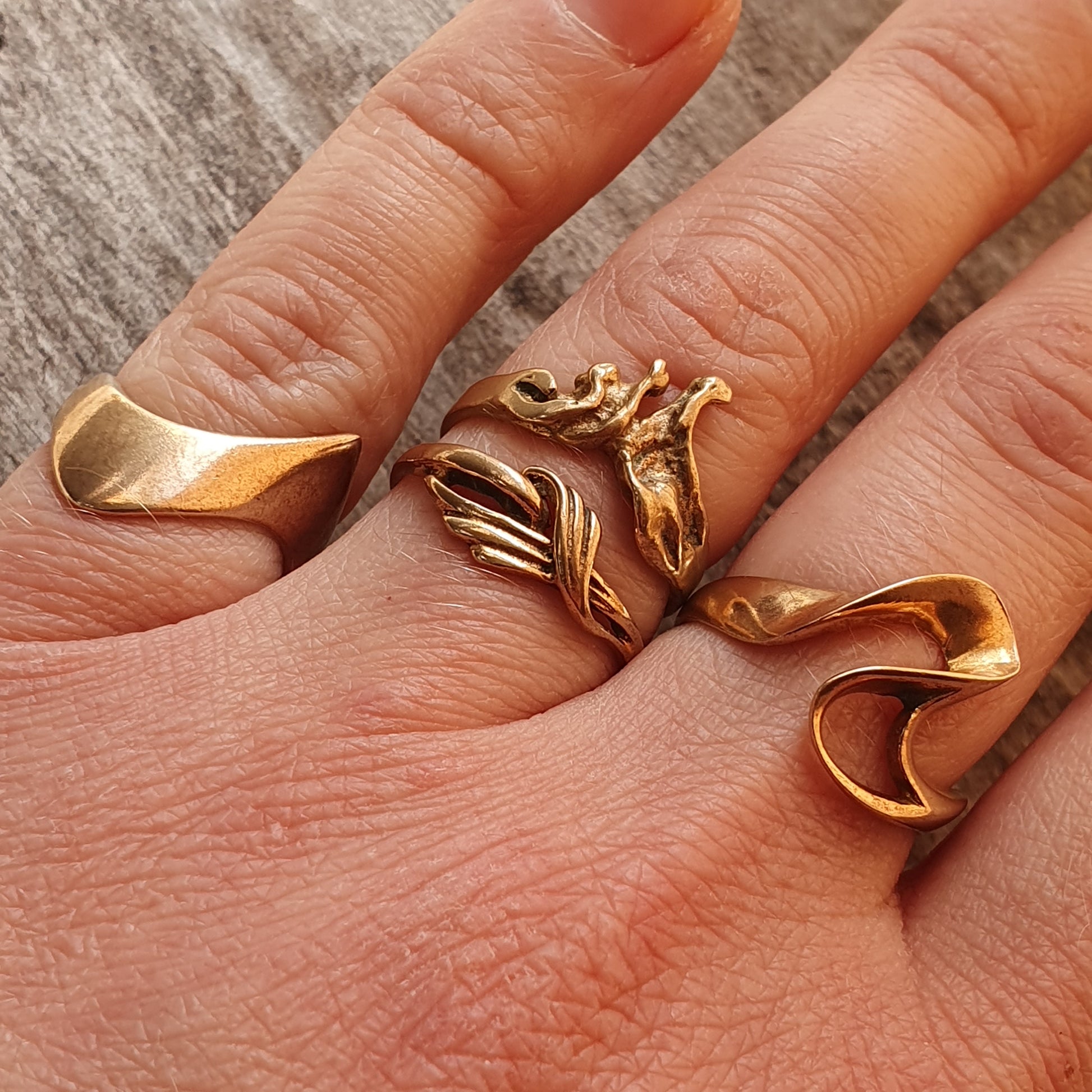 Gold-colored sculptural ring with abstract, flowing forms spanning multiple fingers.