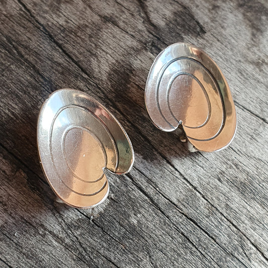 Pair of silver oval-shaped earrings with concentric spiral designs.