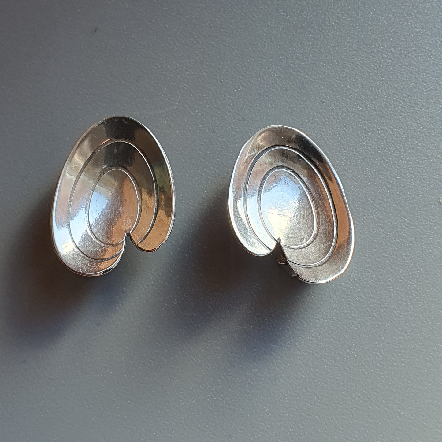 Pair of silver-colored, spiral-shaped earrings or jewelry pieces.