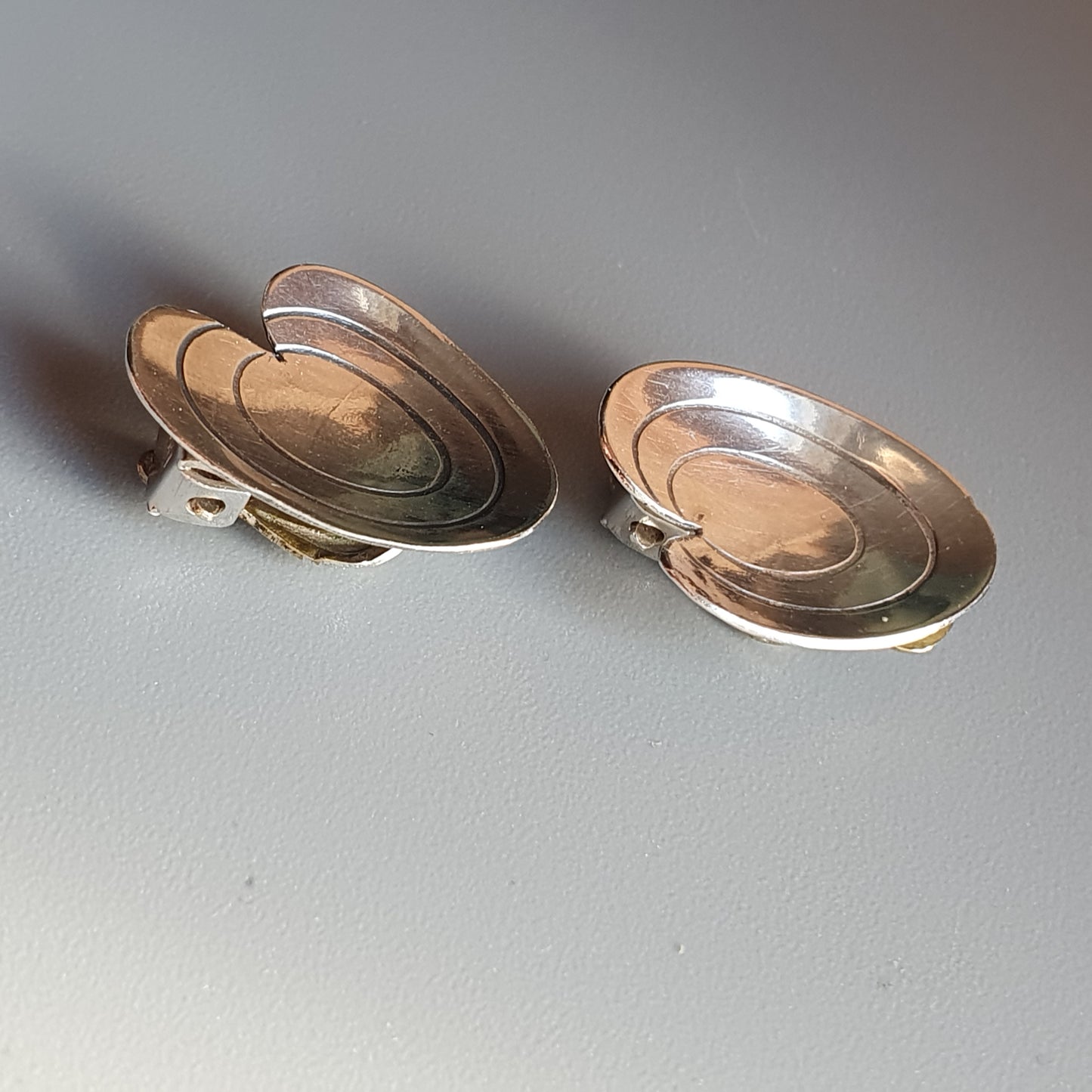 Pair of oval-shaped silver and gold earrings with concentric designs.