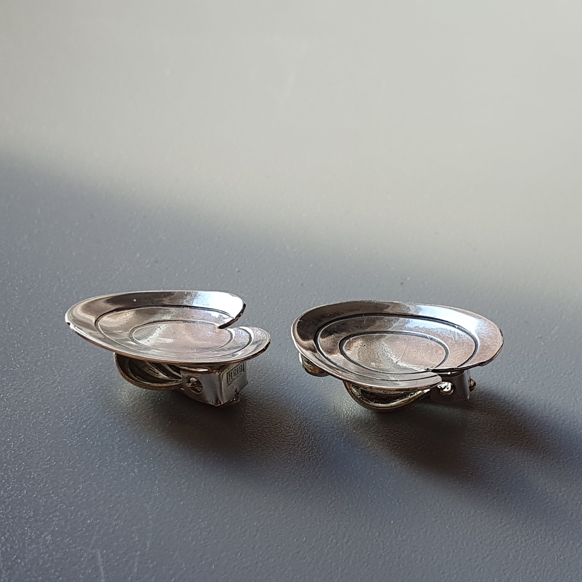 Pair of silver-colored metal salt cellars or small dishes with handles.