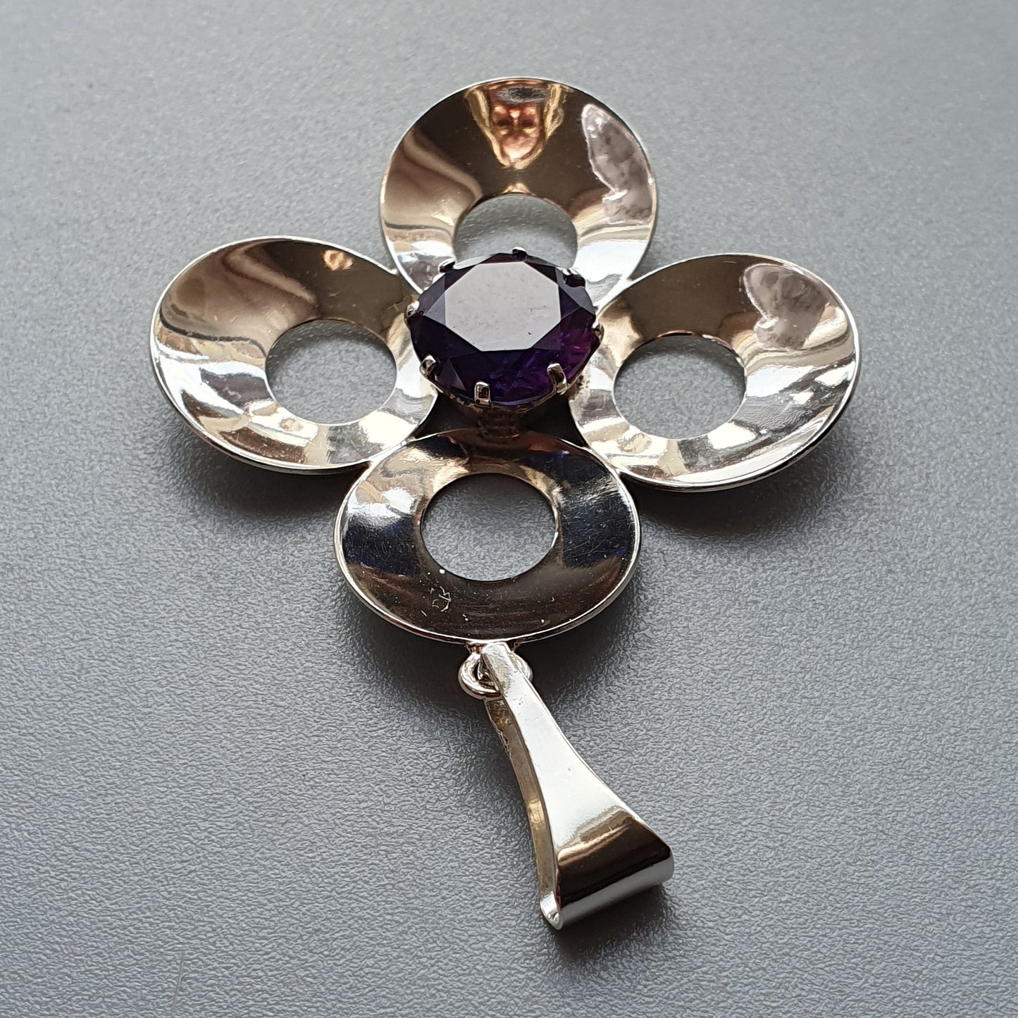 Silver flower-shaped pendant with a purple gemstone center and a small dangling charm.