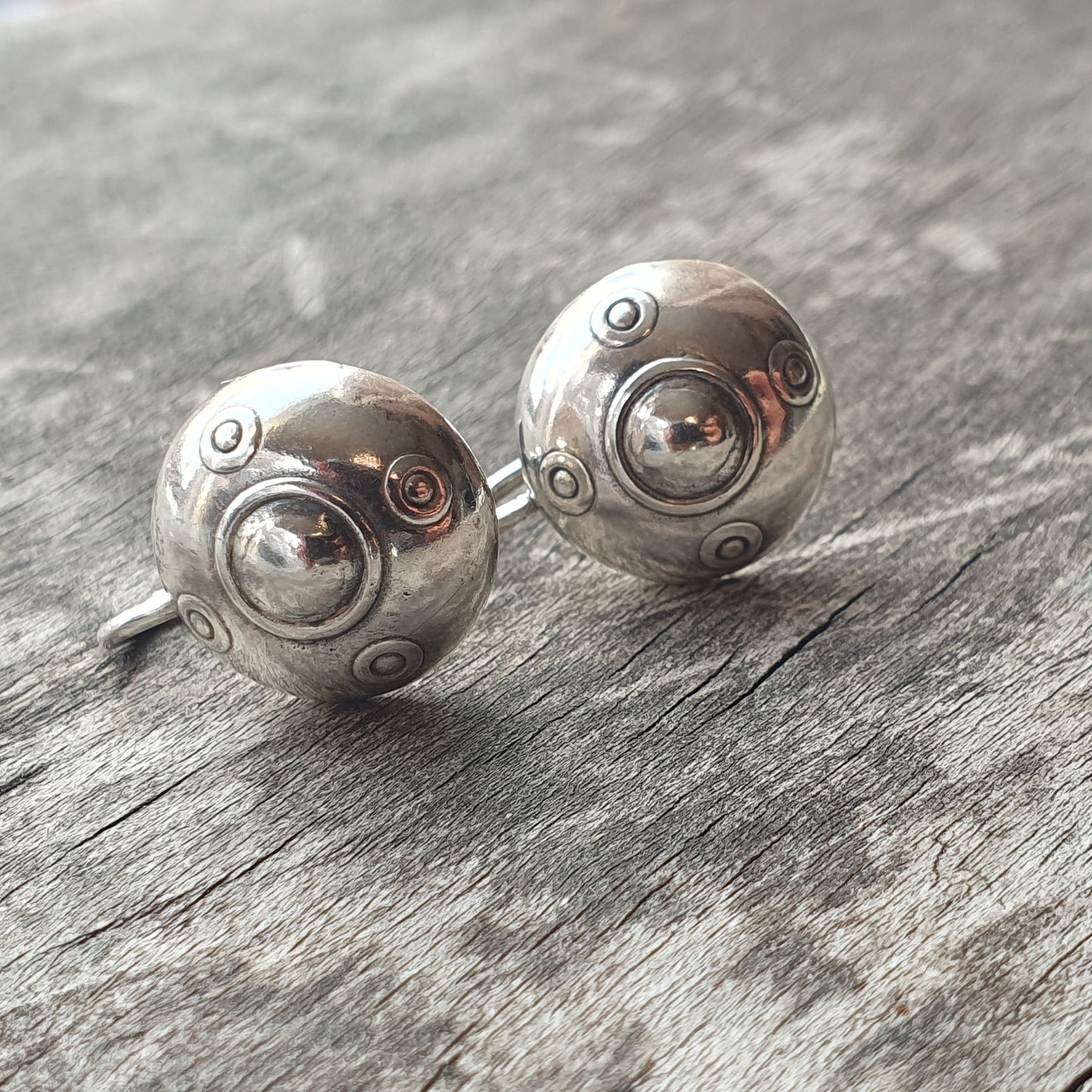 Pair of silver spherical earrings with decorative indentations and raised dots.