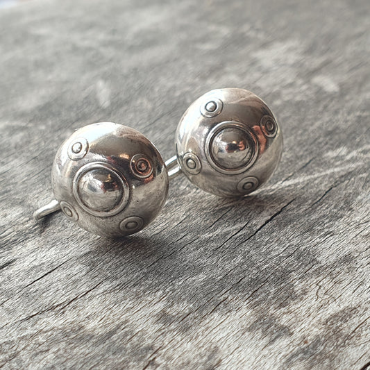 Pair of silver spherical earrings with decorative indentations and raised dots.