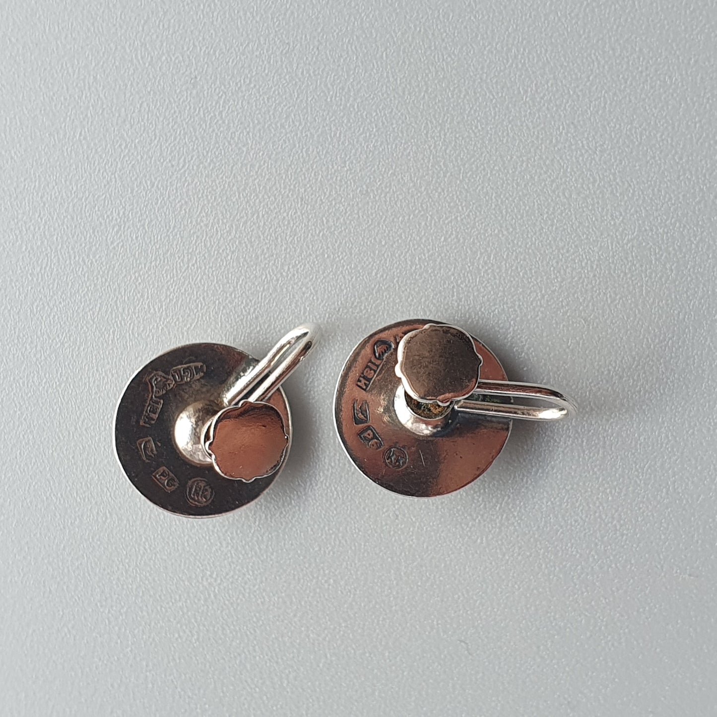 Pair of circular metal earrings with small hoops attached.