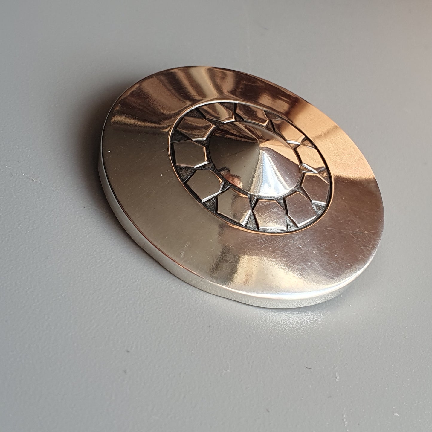 Metallic disc with a spiral cut-out pattern and a central cone-shaped protrusion.