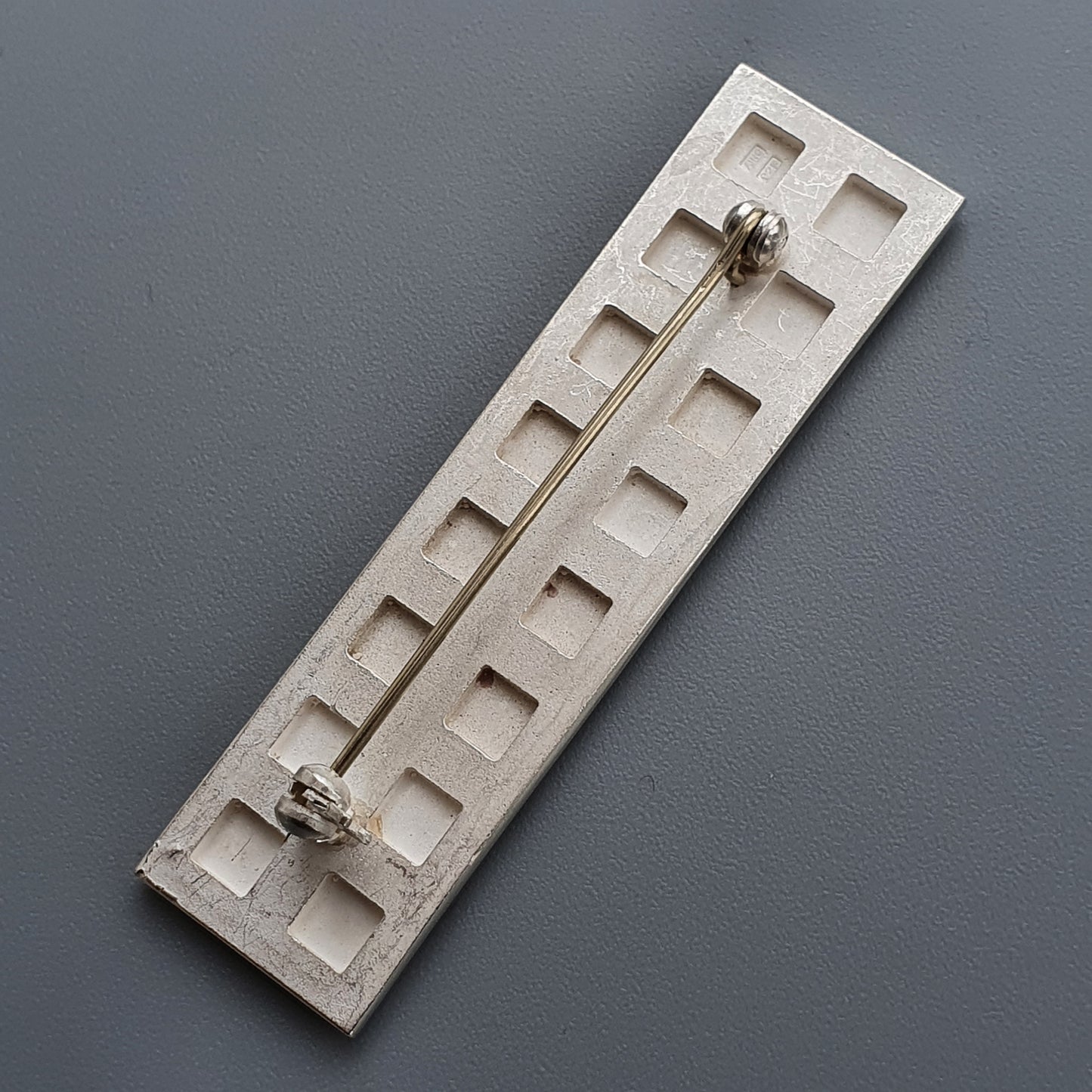 Concrete slab with indentations and latch complementing Finnish Minimalist Rectangular Silver Brooch