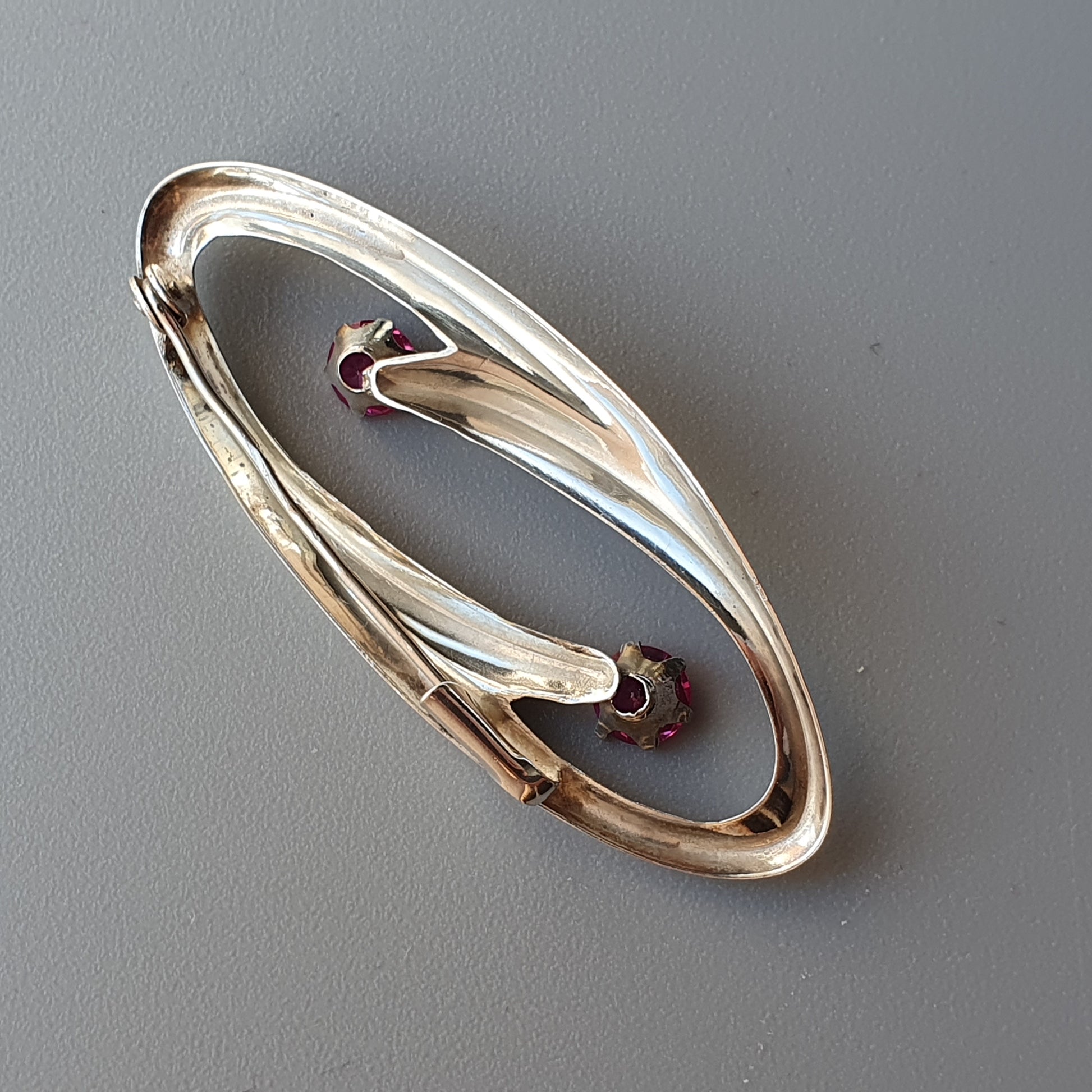 Elegant oval-shaped gold bracelet with curved design elements and gemstone accents.