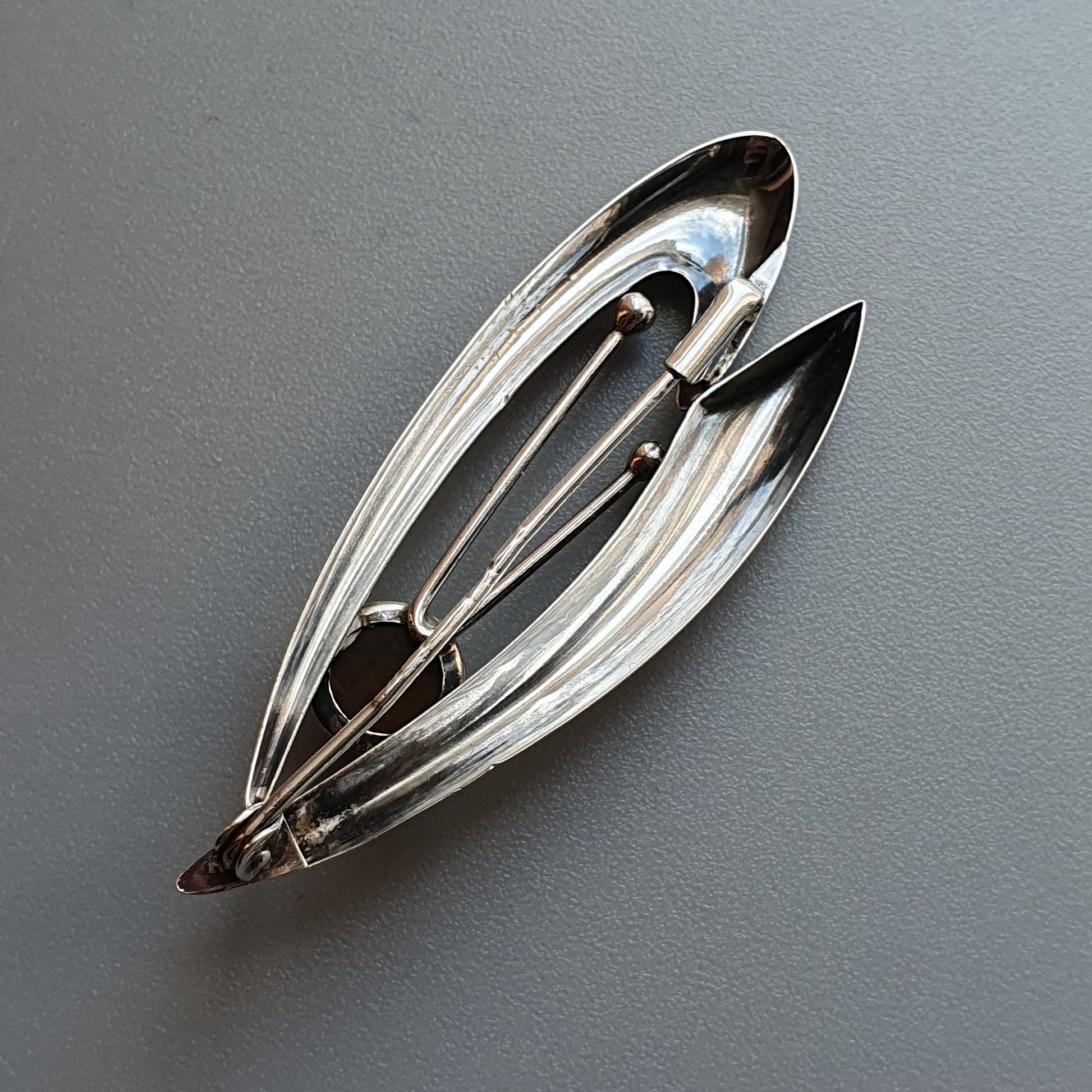 Sleek silver brooch shaped like elongated leaves or petals.