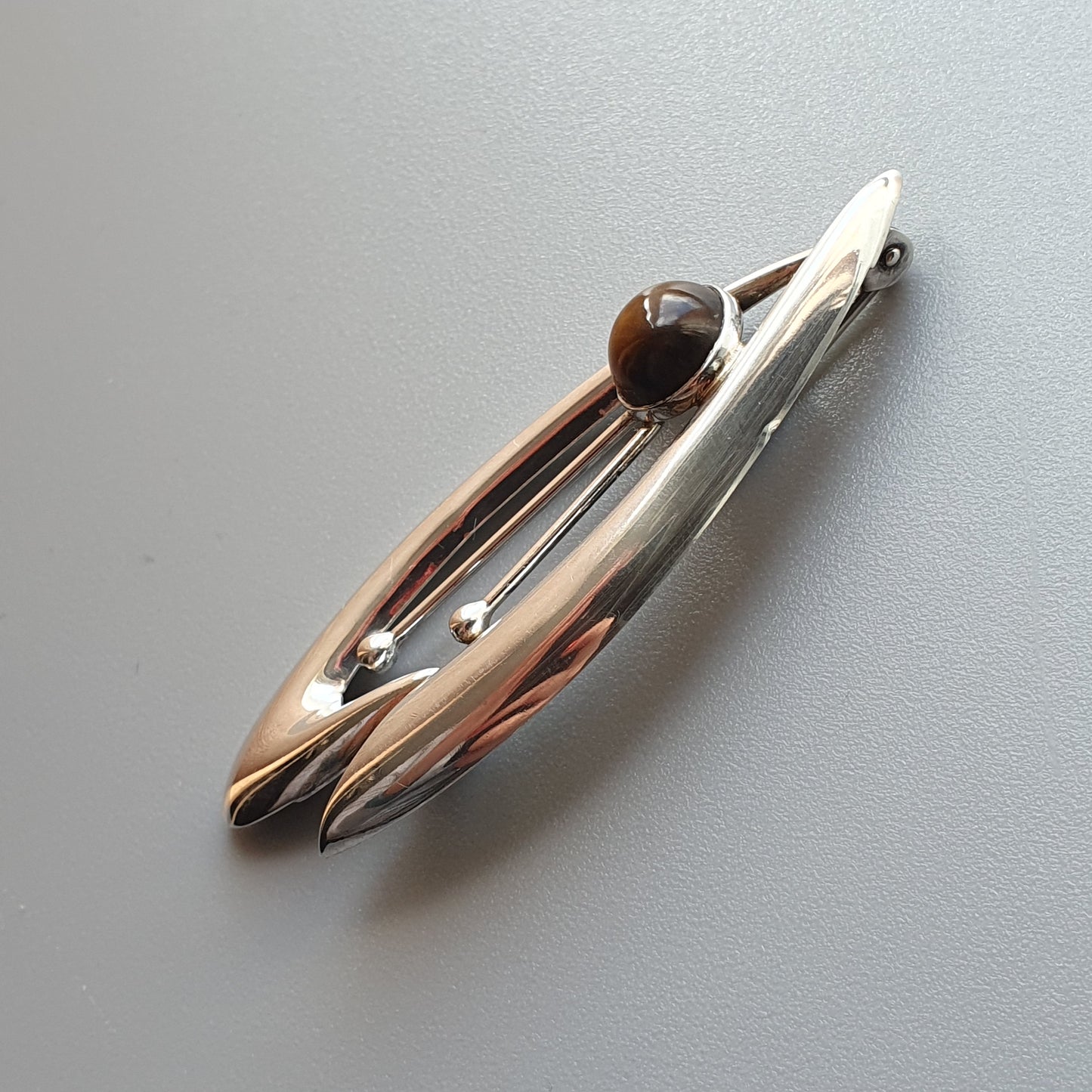 Sleek, metallic hair clip or barrette with a spherical accent.