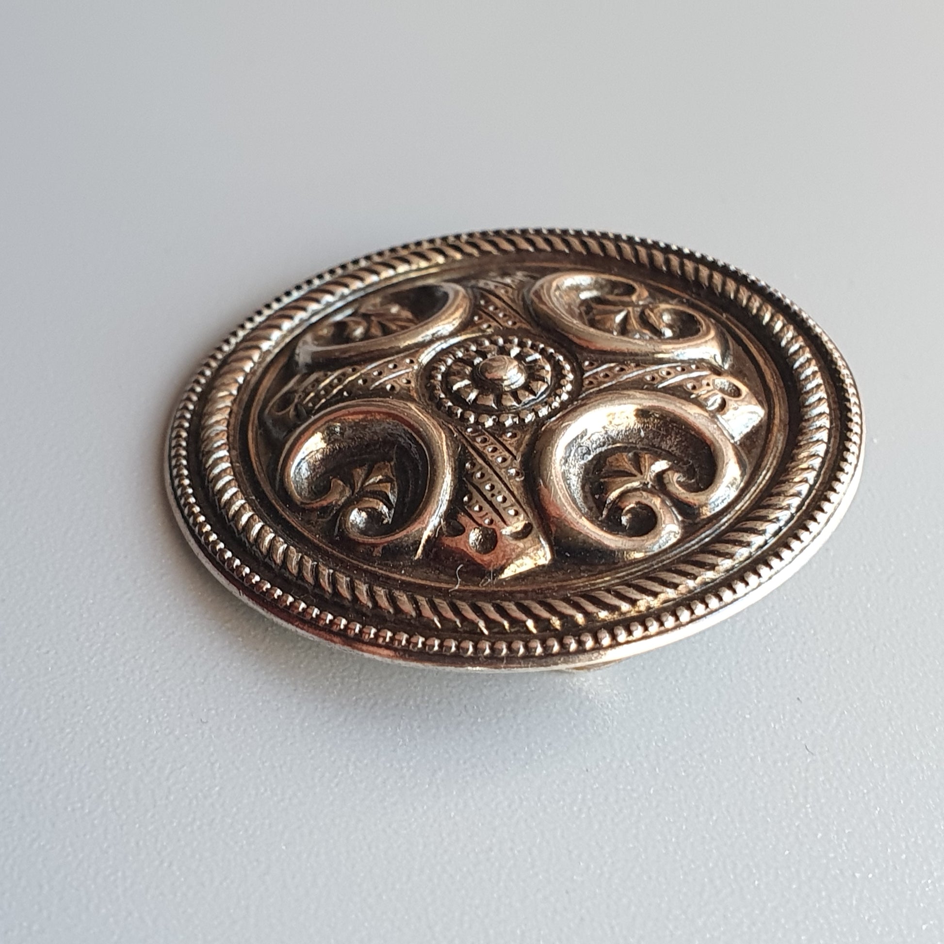 Ornate silver belt buckle with intricate floral and scroll designs.