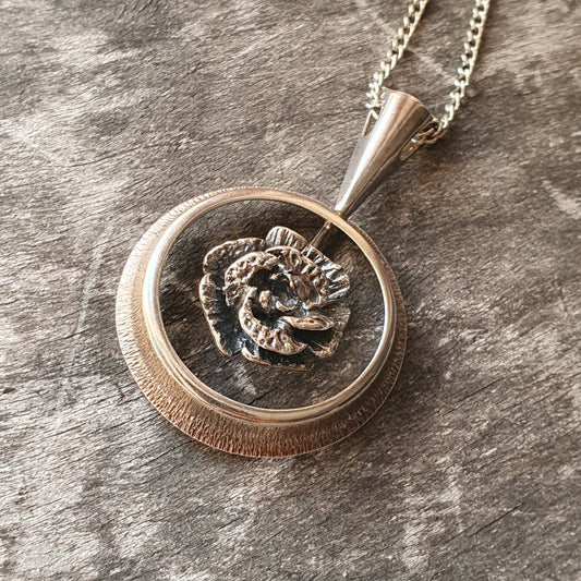 Circular pendant necklace featuring a relief design of a lion’s head.